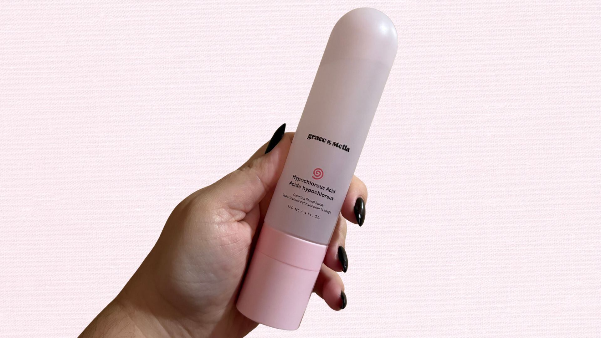 Bianca's hand holding up the bottle of facial spray with a bright background
