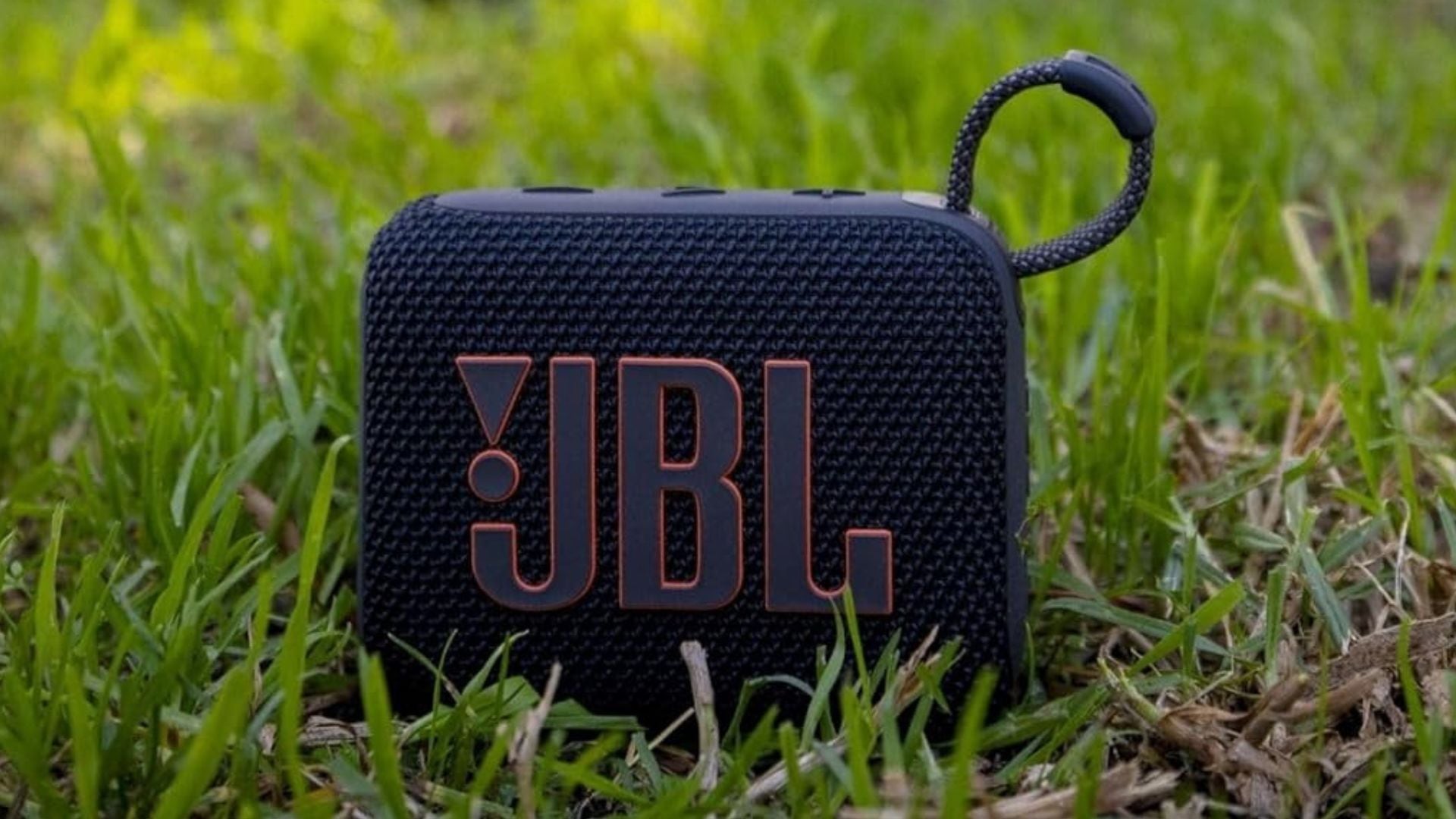 A black JBL Speaker on a lawn.