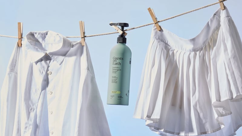 A bottle of Guests on Earth detergent hanging from a clothesline.
