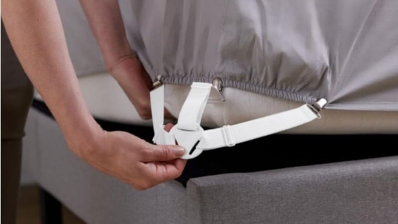 Someone installing a bed sheet holder strap