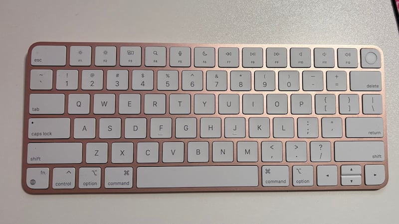 A pink Mac Magic keyboard on a plain desk