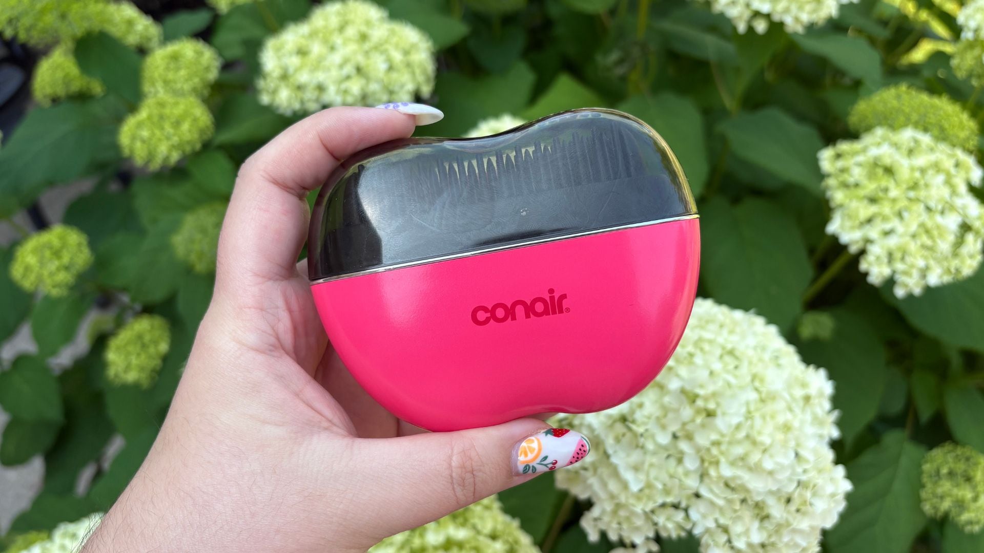 Bianca holding the cordless brush in front of some flowers