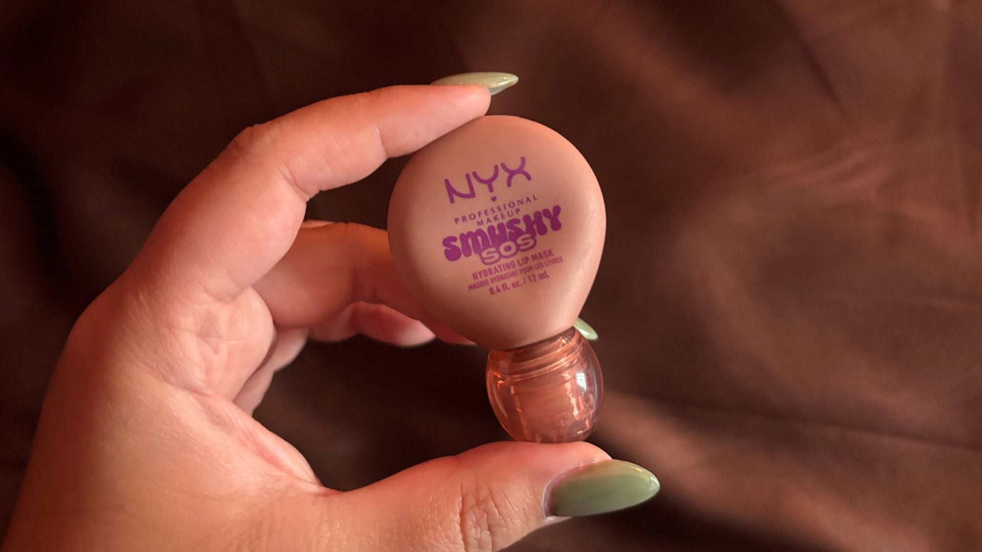 Bianca holding the lip balm with a dark and moody background