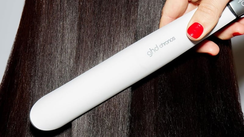 a person putting the flat iron through their sleek hair