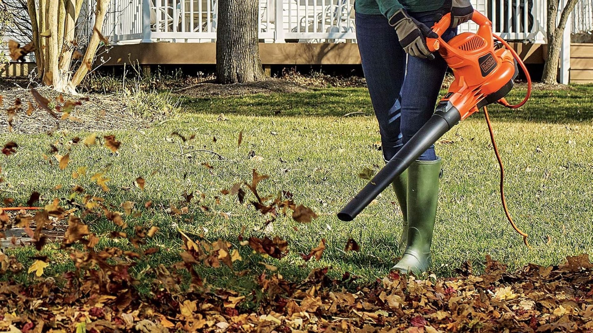 A person clearing leaves from their lawn with a Black+Decker Leaf Blower