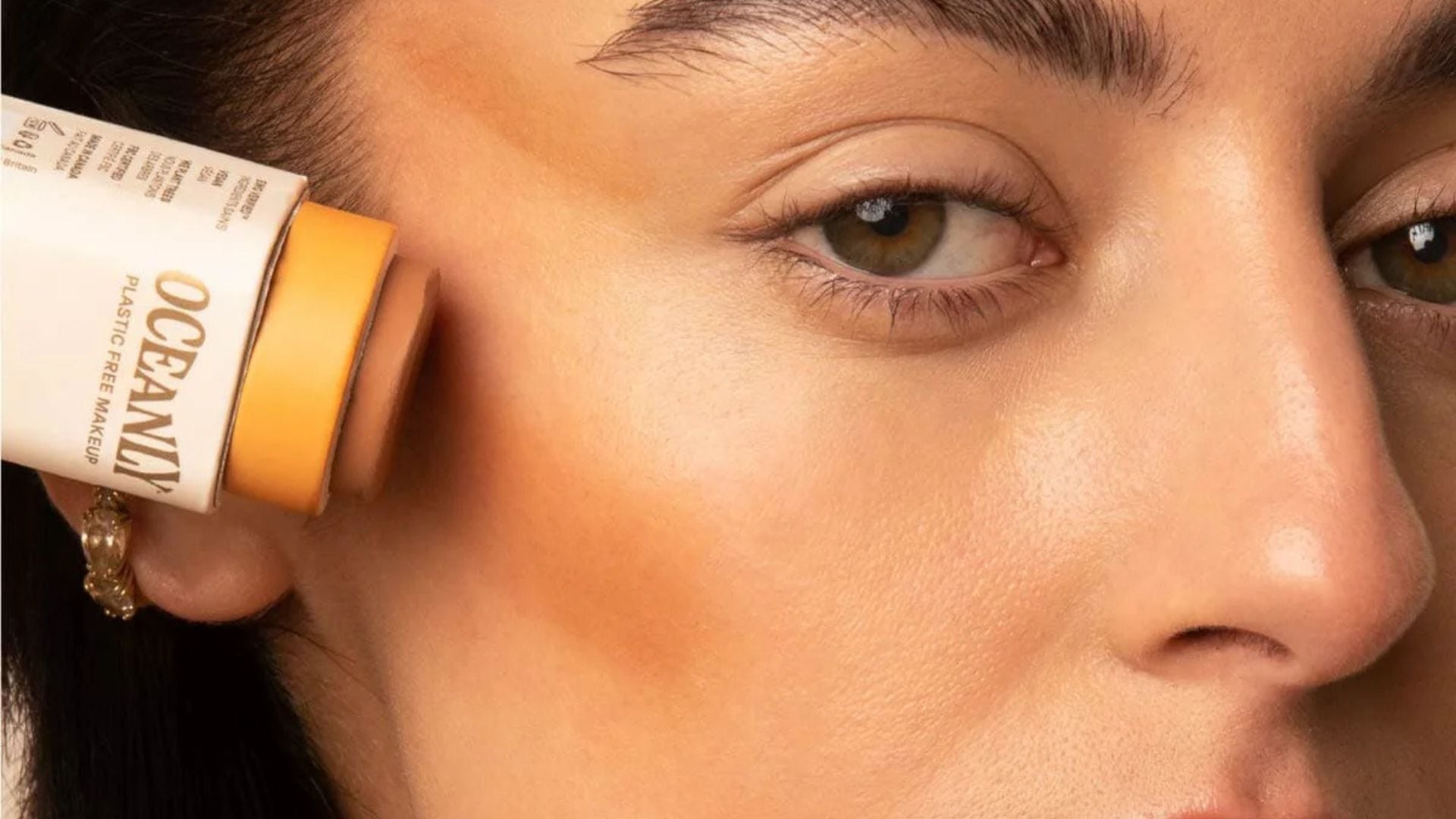 a model putting bronzer on her cheek