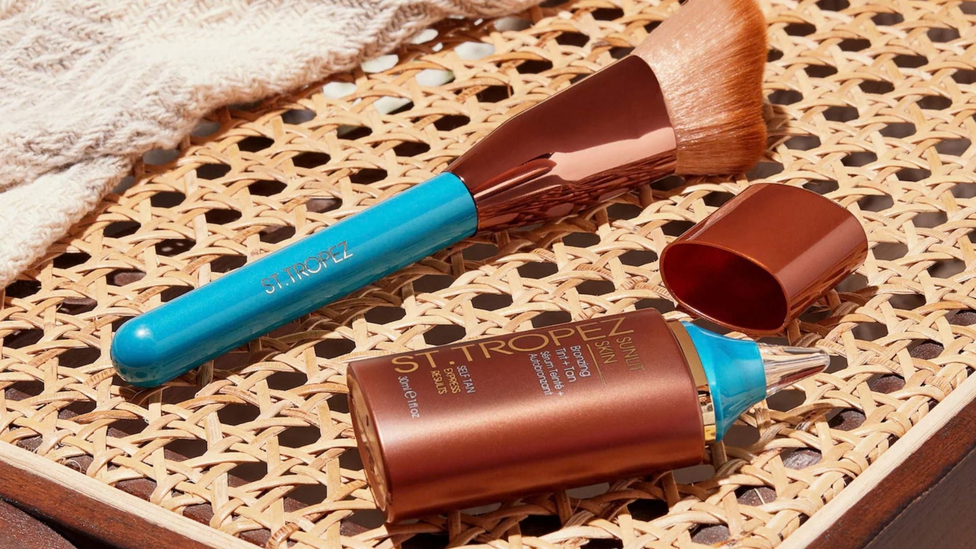 St. Tropez Face Tanning Serum on a wicker table next to a makeup brush.