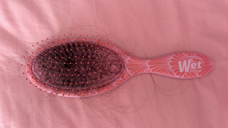 a hair brush with a lot of hair in it