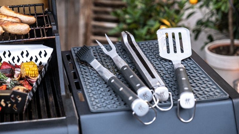 Four Zwilling BBQ tools lay out on the side of a barbecue.