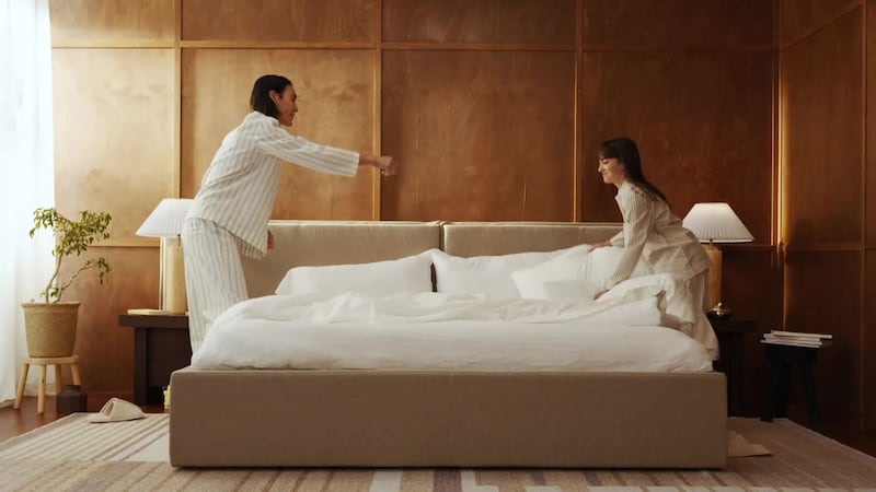 two people making a bed in a bedroom