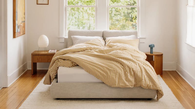 an unmade bed in a cozy bedroom under a window