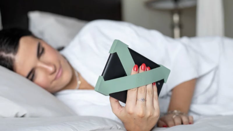 A person using the Strapcicle to hold onto their eReader while they lay in bed.