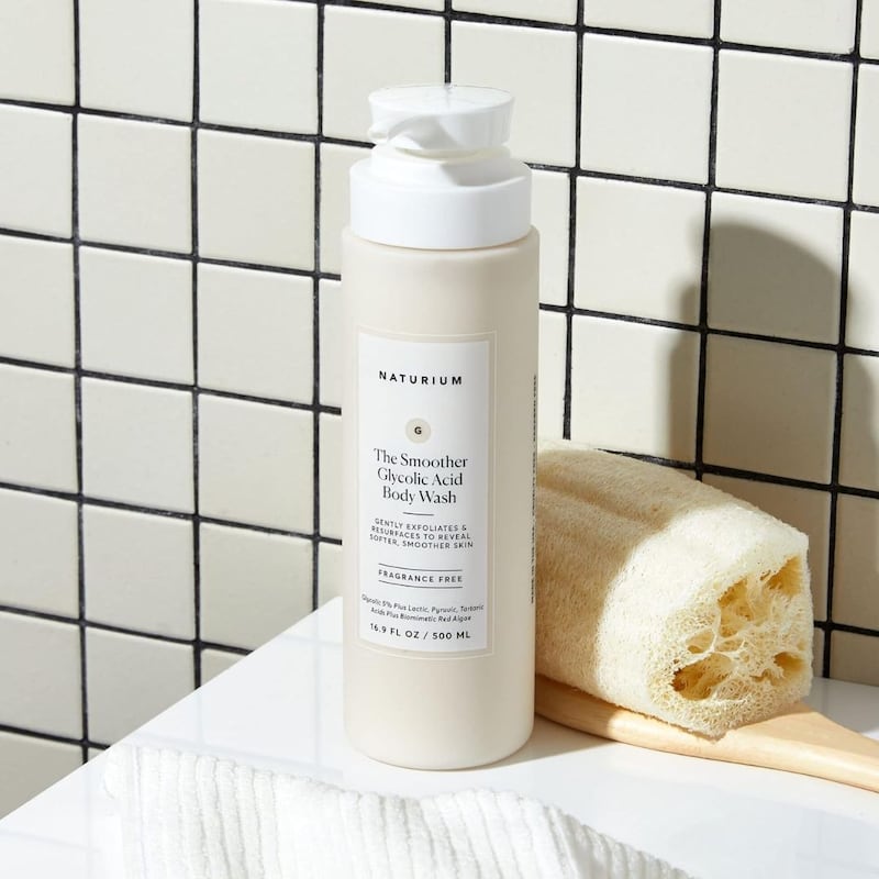 A bottle of Naturium body wash next to a loofah.