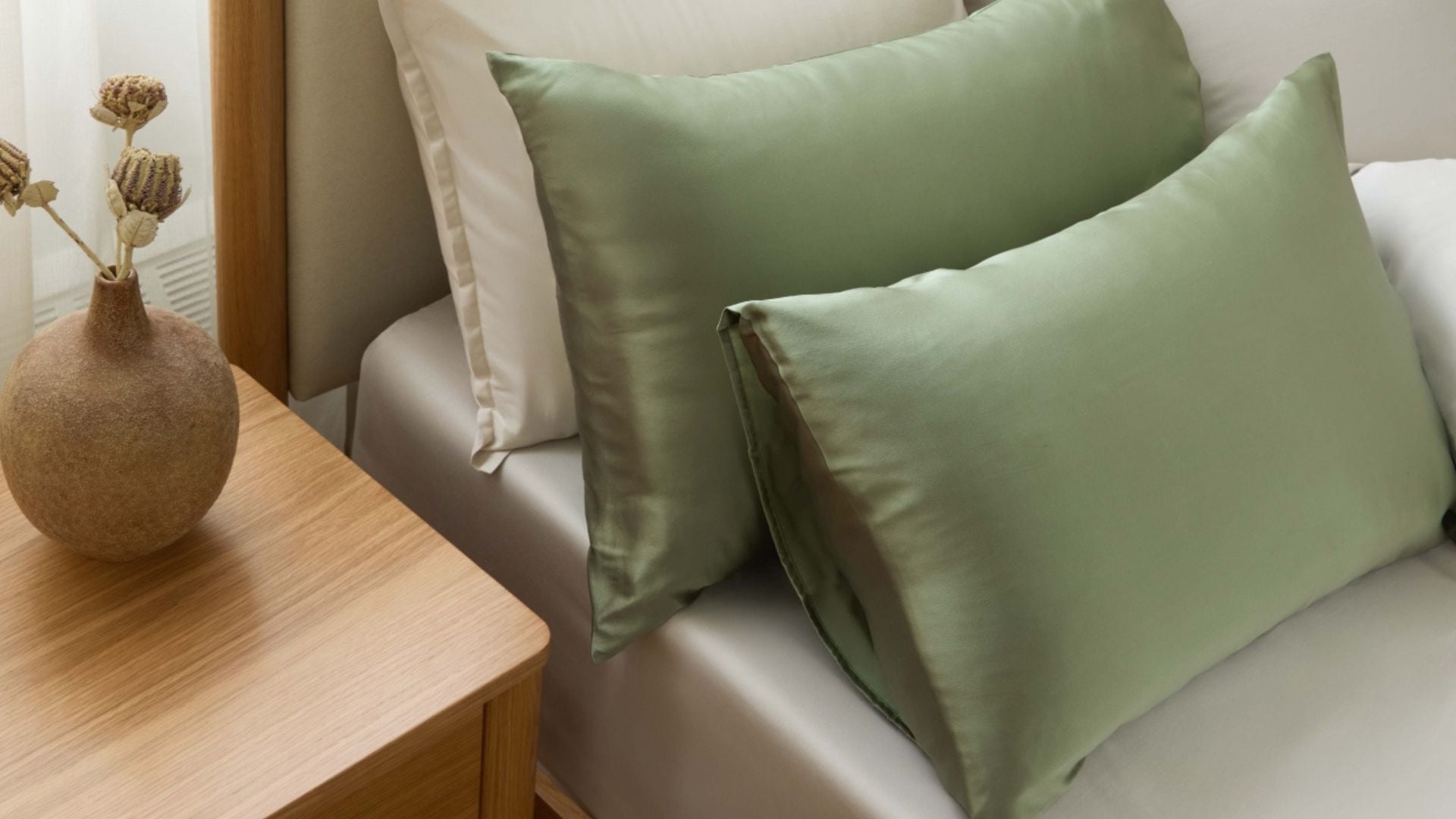 Two silk pillowcases on a bed with other Silk & Snow bedding.