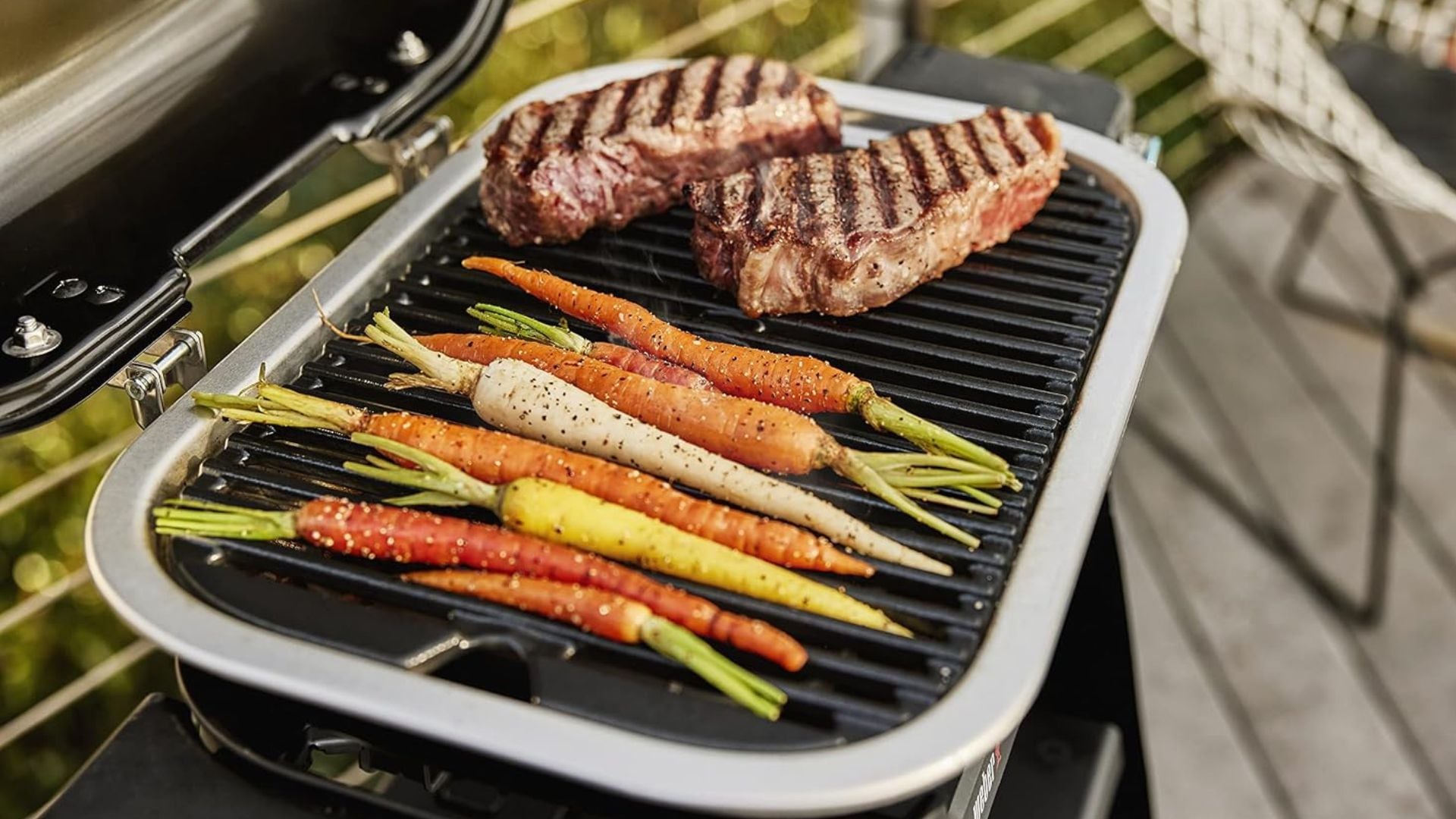 Carrots and two steaks on a Weber Grill.