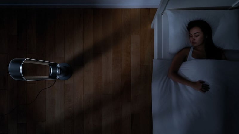 A Dyson fan next to a person in bed.