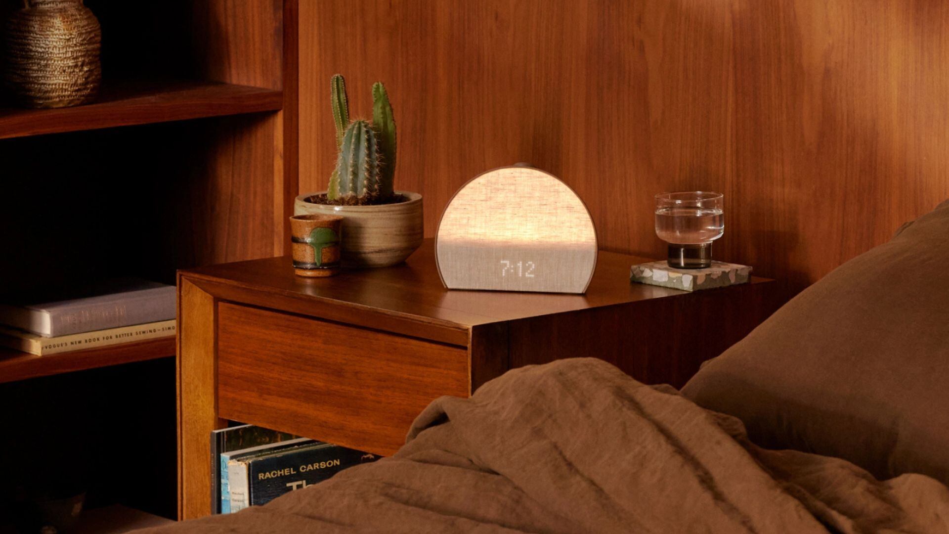 a Hatch alarm clock on a side table next to a bed