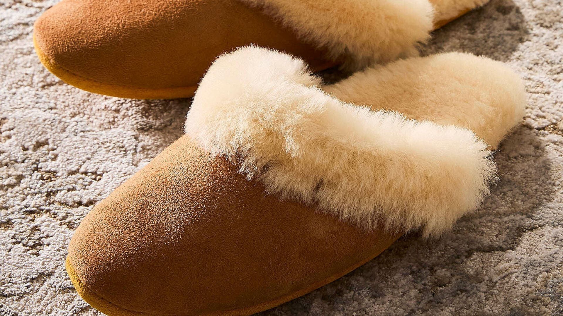 a pair of fluffy sheepskin slippers on a rug