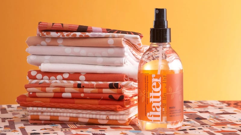 A bottle of Soak wrinkle spray next to a pile of linens.