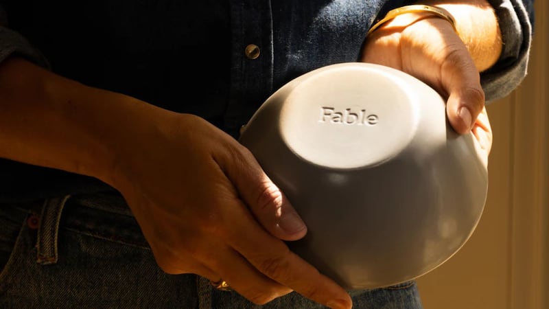 a person holding a bowl upside down to reveal the Fable marking
