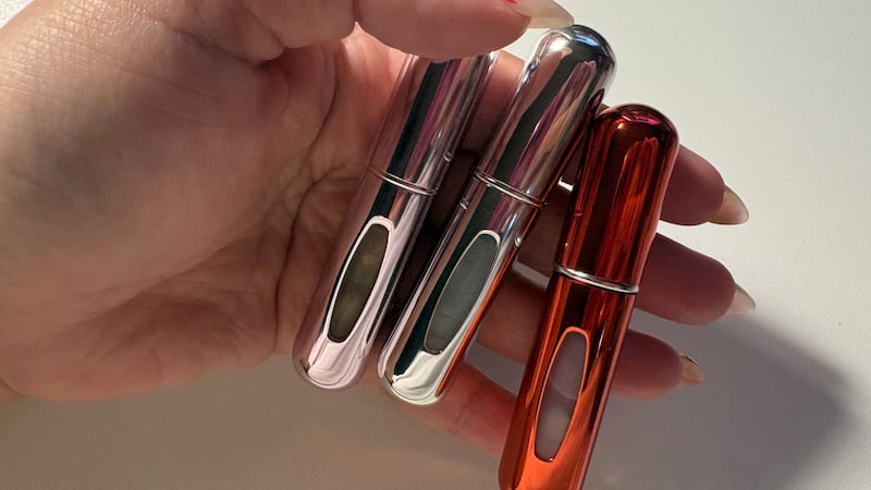 Bianca holding three of the mini atomizers that are full with different perfumes