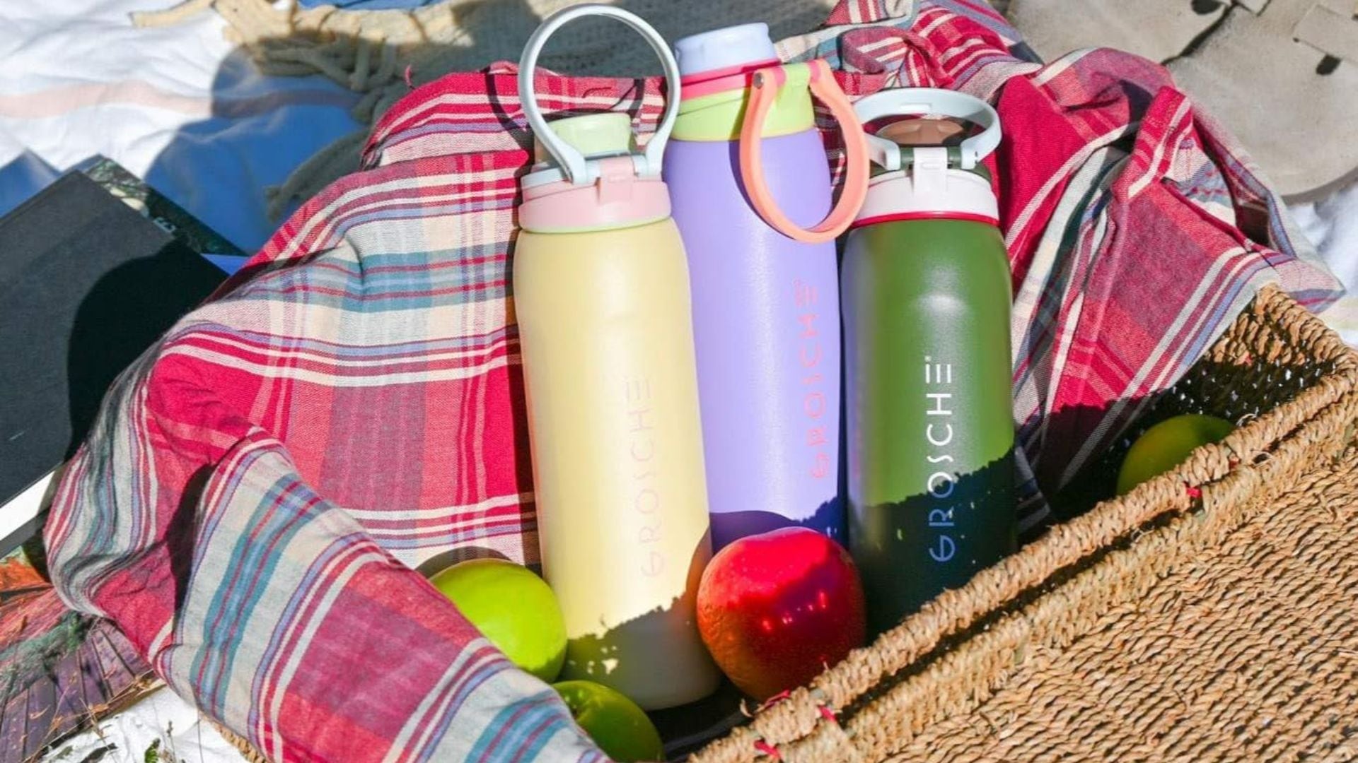three water bottles in a basket on the beach