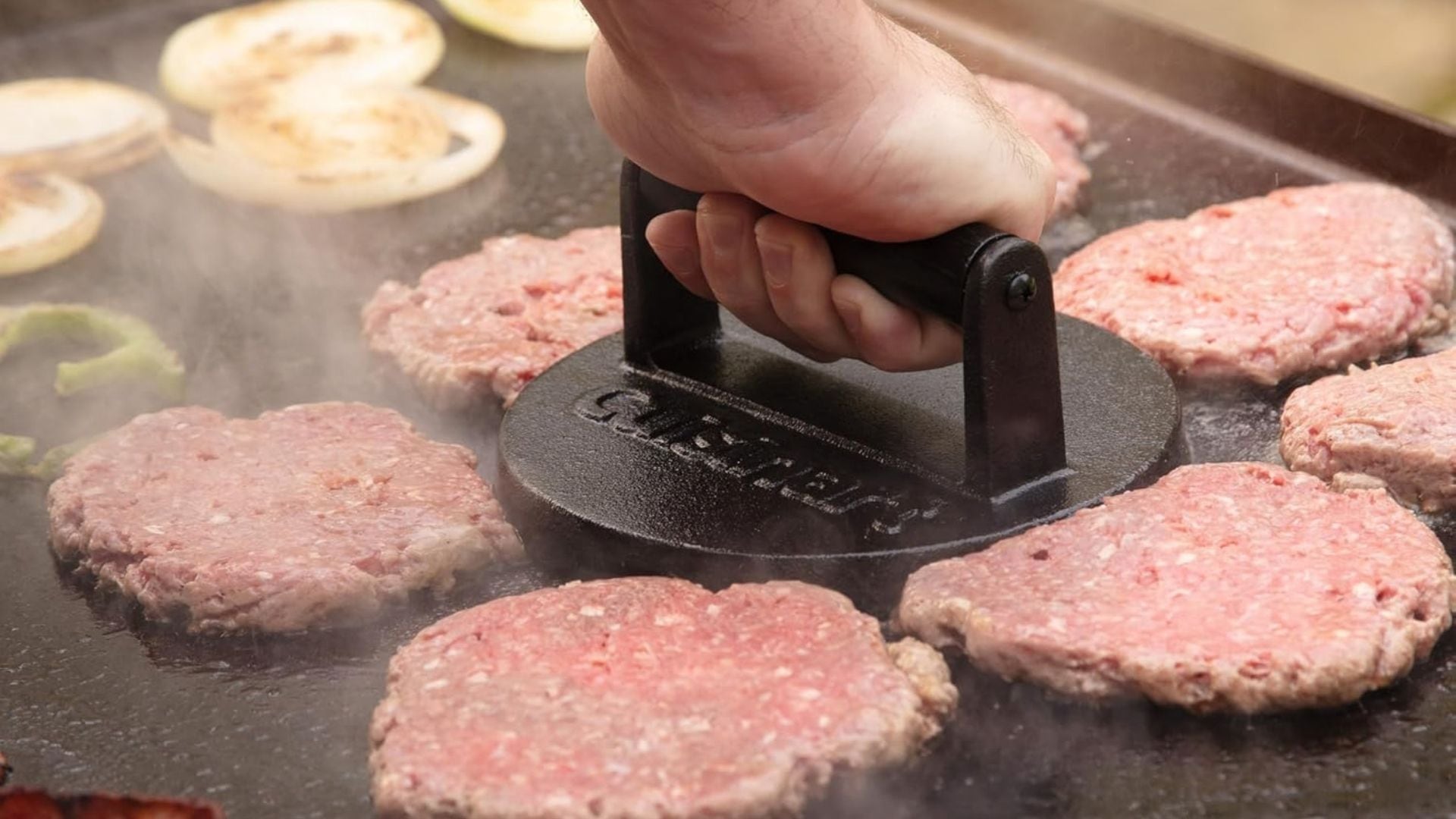 A person smashing a burger patty with the Cuisinart cast iron burger press.