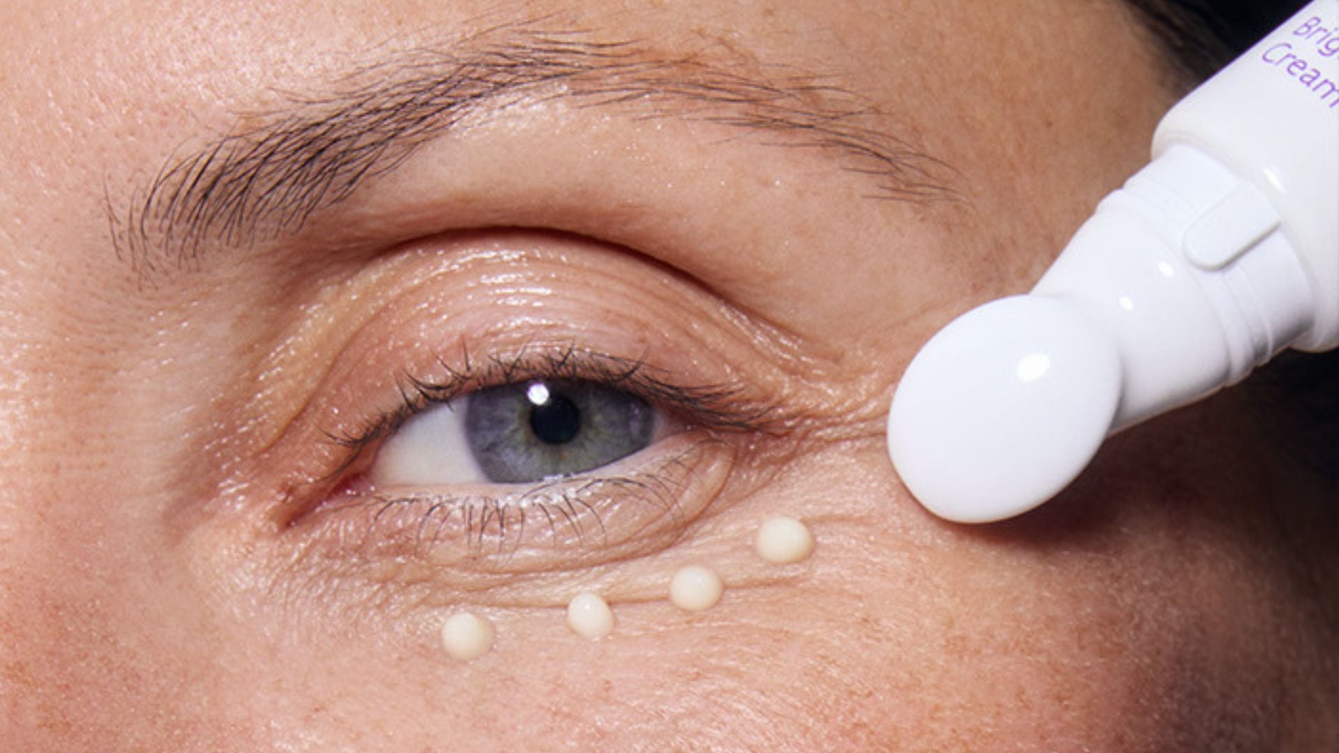 A person applying eye cream.