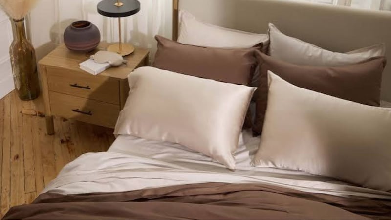 A set of silk pillowcases displayed on a bed with other Silk & Snow bedding.