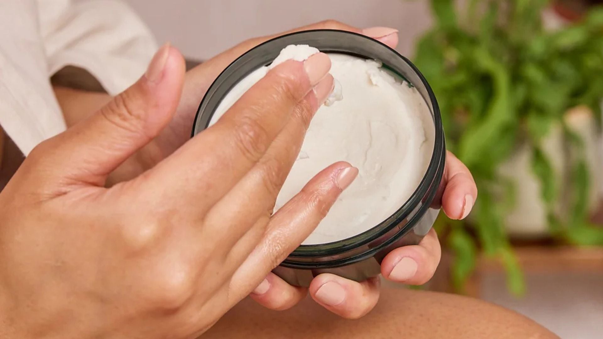 a person dipping their fingers into a tub of cream