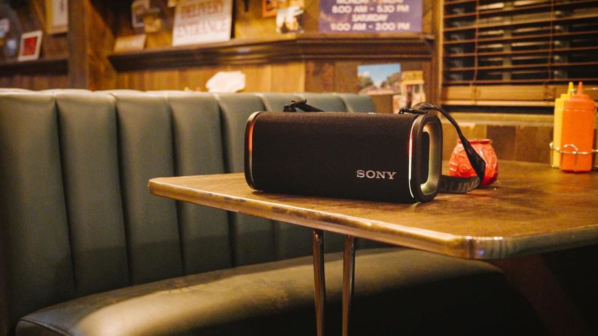 A Sony Bluetooth speaker on a table in a diner.