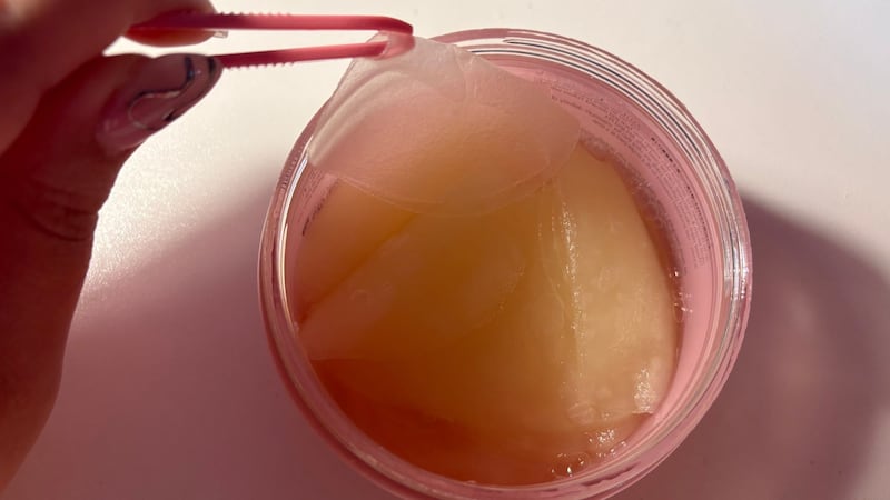 Bianca using the tweezers to get a toner pad out of the container