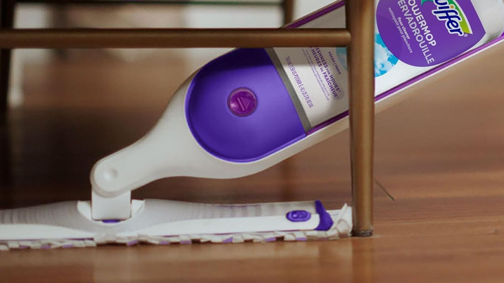 A person using a SWiffer to mop a hardwood floor.
