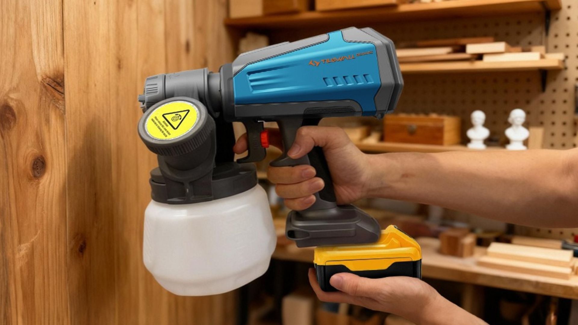A person using the Tilswall Cordless Paint Sprayer to paint a wooden wall.