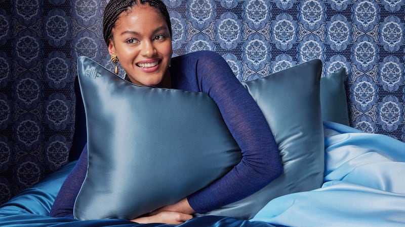 A person hugging a pillow with a blue Slip Silk Pillowcase on it.