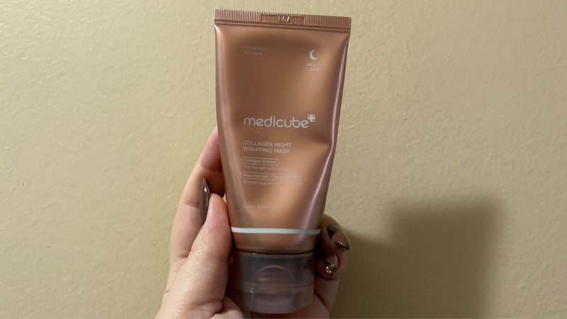 Bianca holding the face mask tube up against a wall