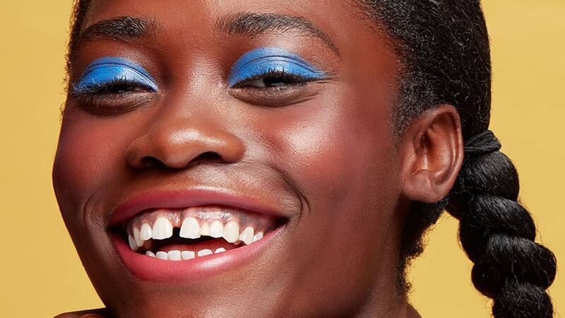 a model wearing colourful eyeshadow smiling