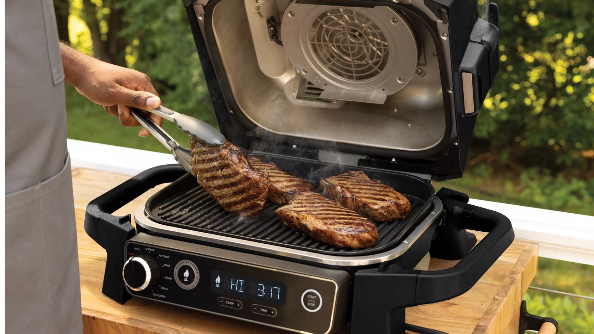 A person Grilling steaks on a Ninja grill.