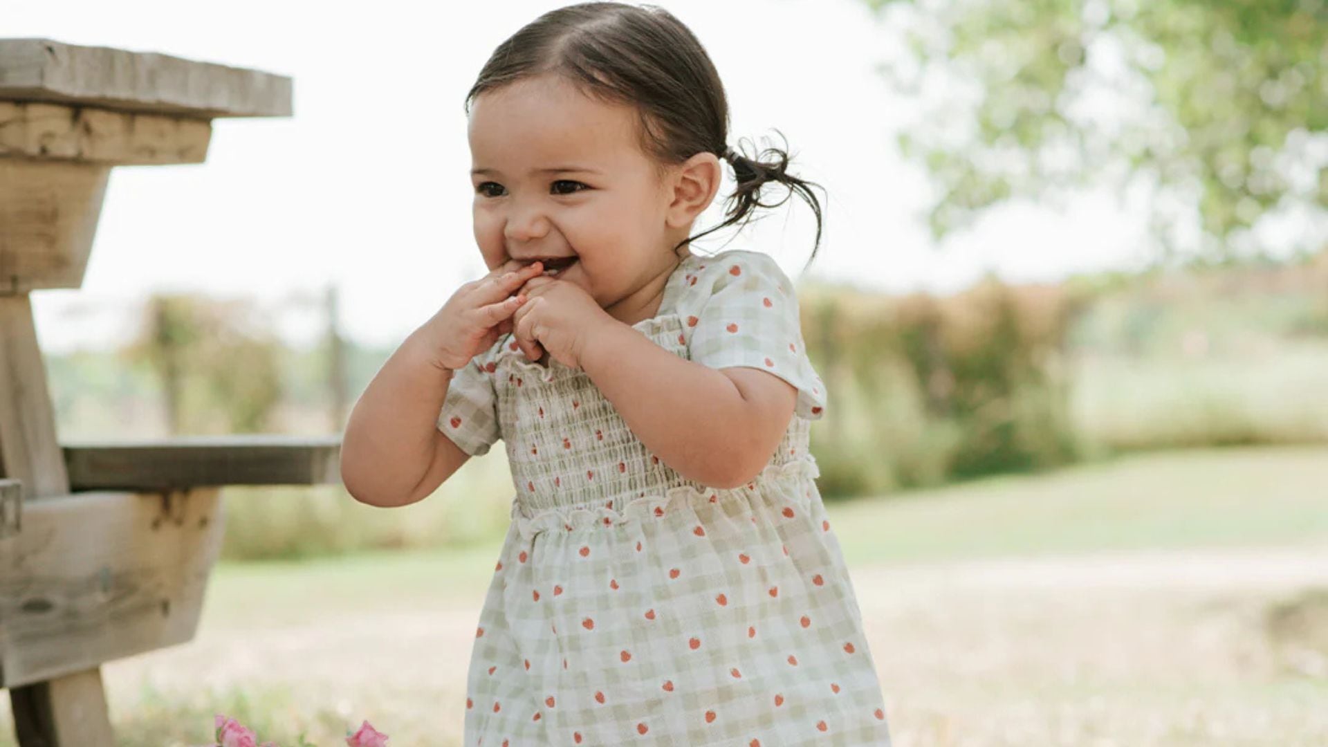 a toddler outside wearing a gingham dress