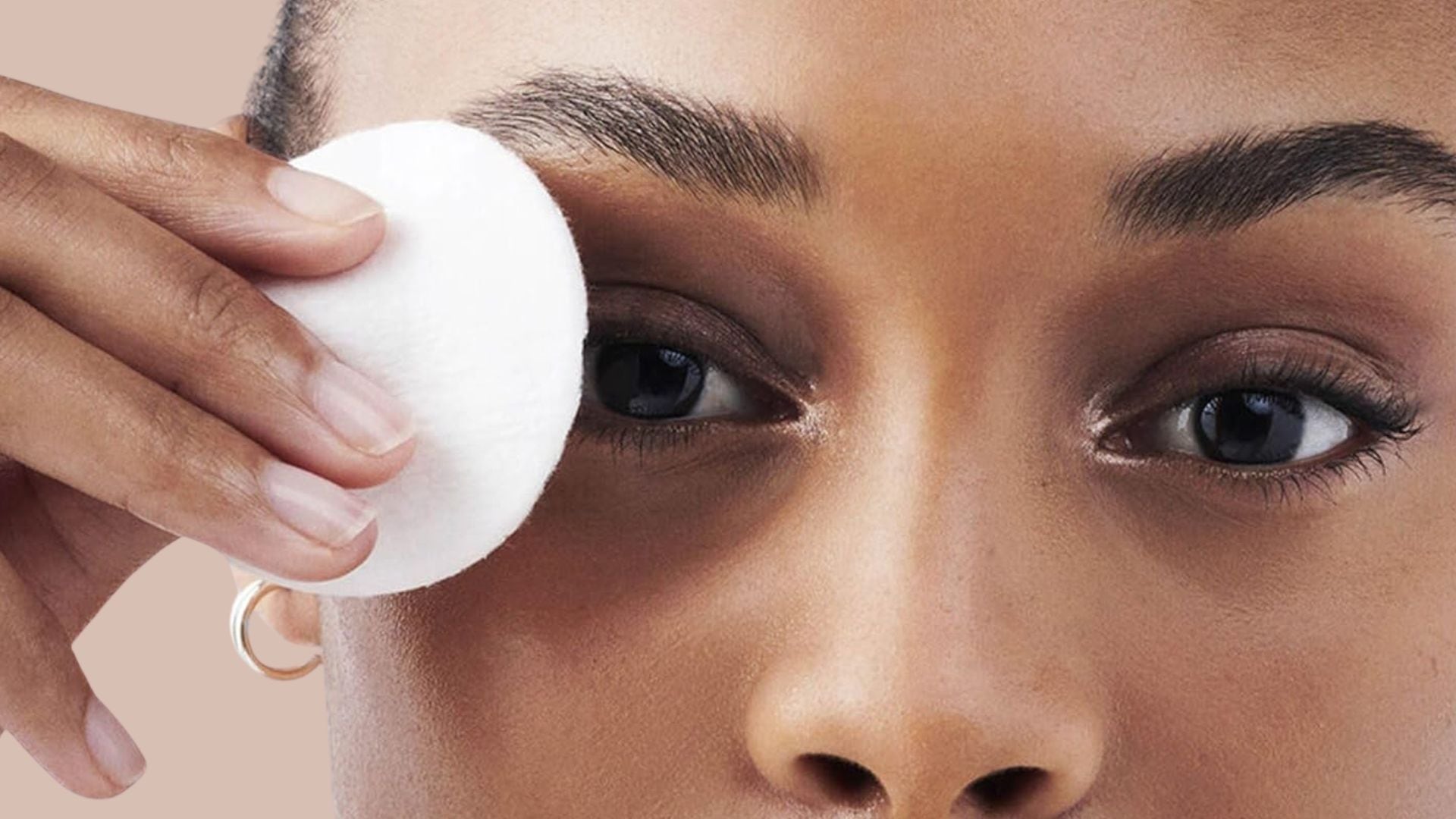A person is removing their eye makeup with a cotton pad.