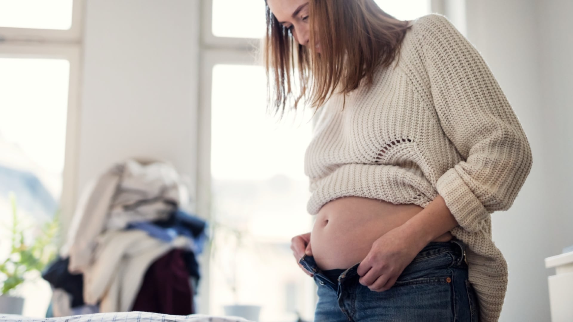Pregnant woman zipping her jeans