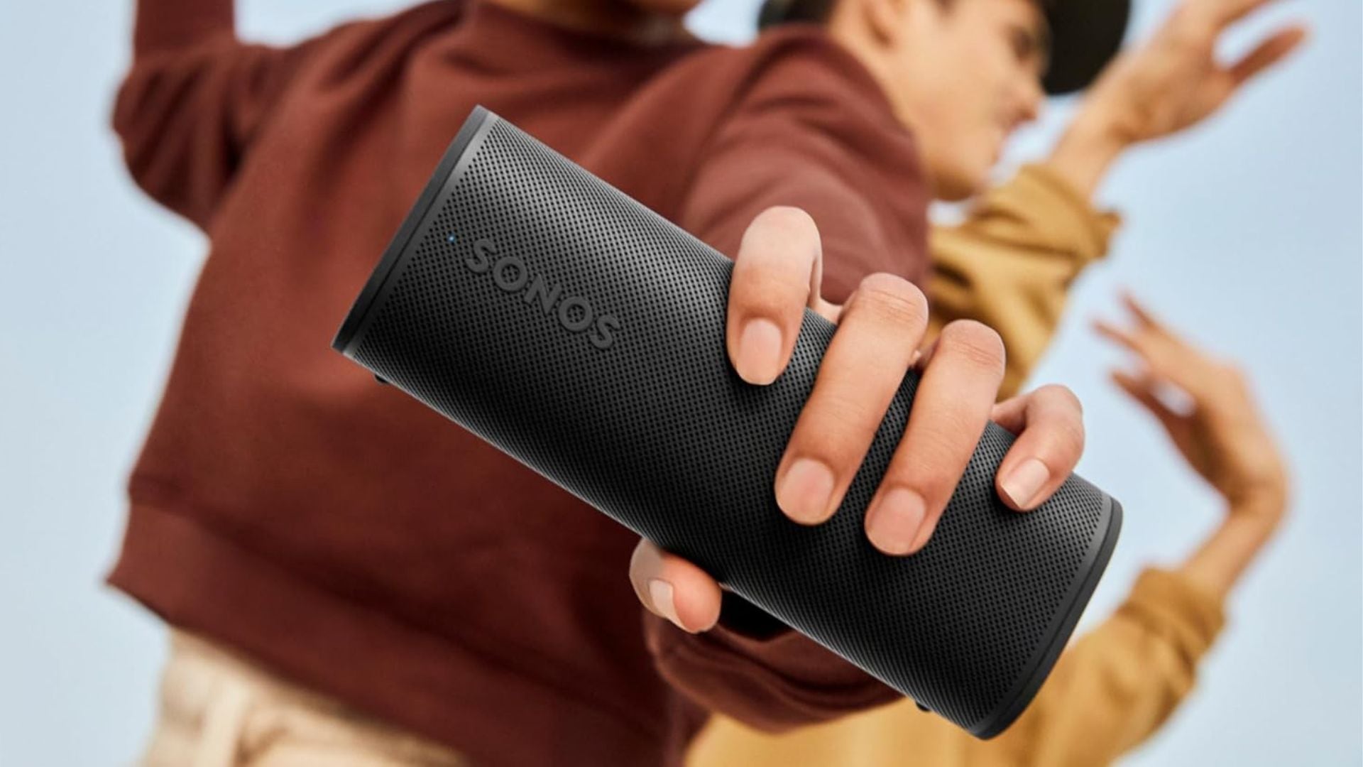 A person holding a Sonos speaker.