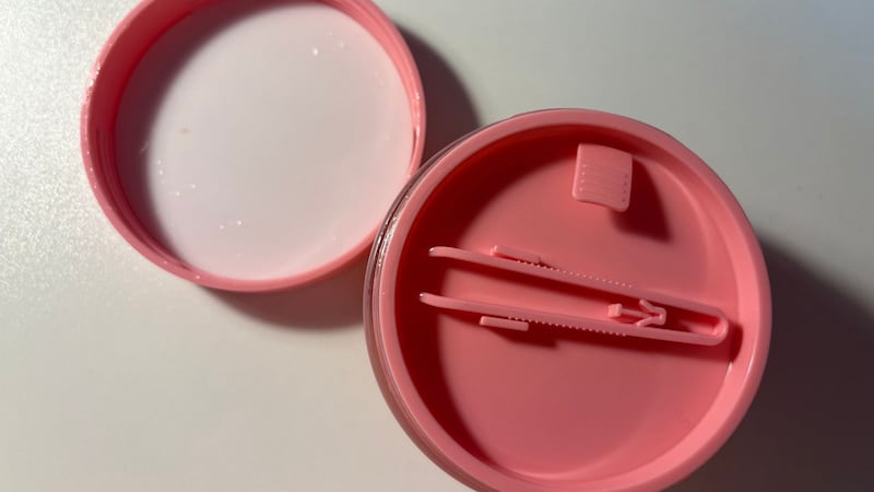 The airtight cap and set of matching tweezers on the top of the container of toner pads