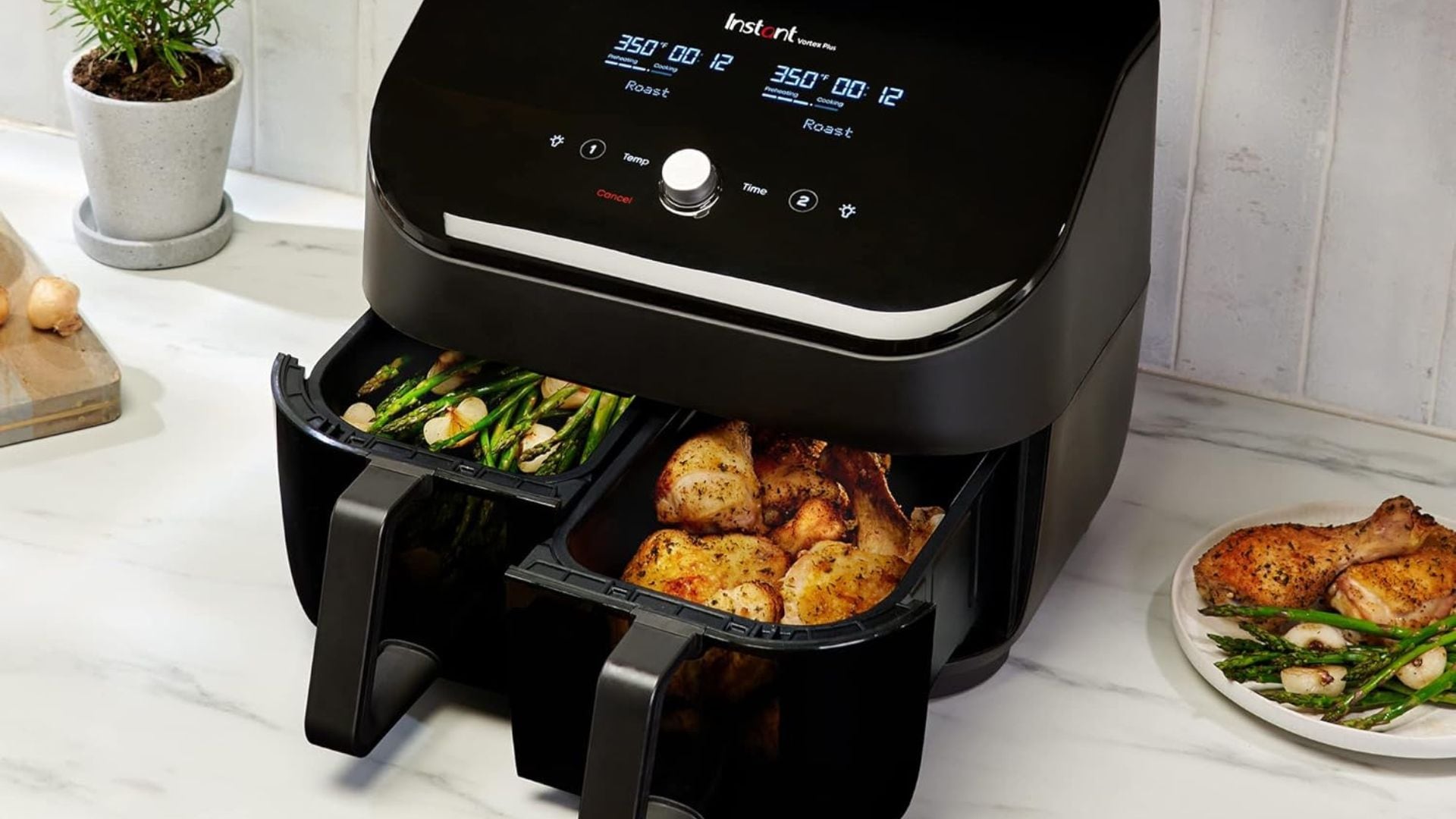 A dual basket air fryer is cooking veggies and chicken.