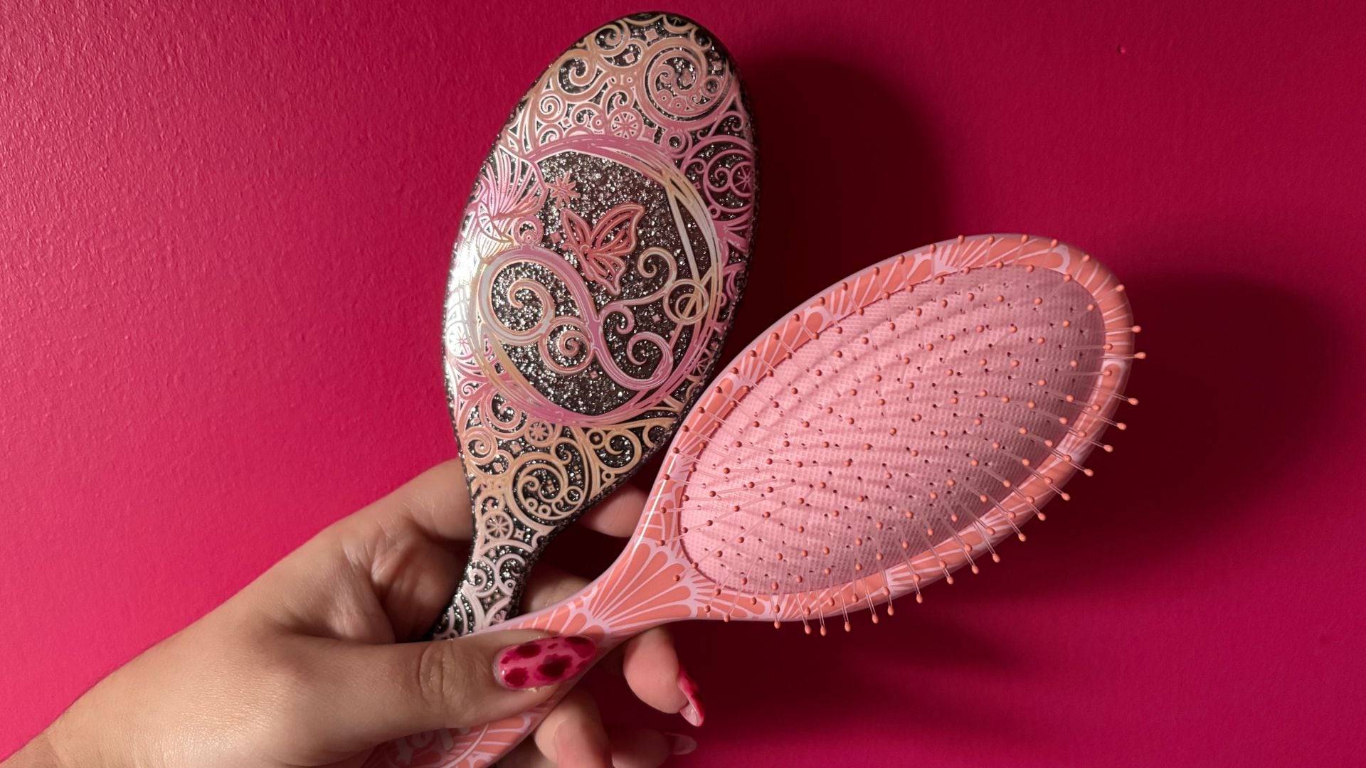 Bianca holding up two wet brushes against a bright plain wall
