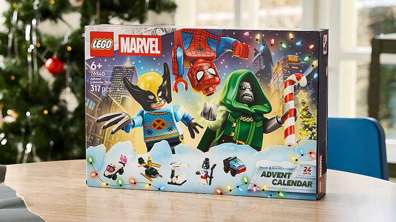 A LEGO Marvel Advent Calendar on a table in front of a Christmas tree.