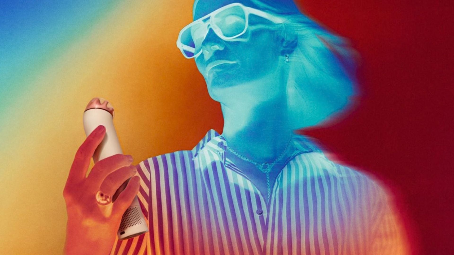 A woman wearing sunglasses is using a Dyson handheld fan.