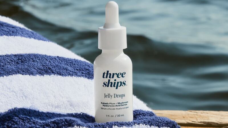 a facial serum on a towel by a lake