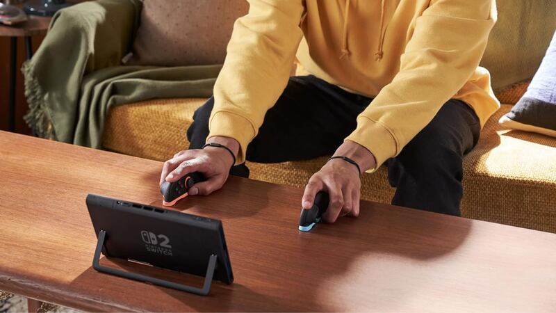 A person playing the Nintendo Switch 2 with the Joy-Cons detached. The console rests on a table with its kickstand up.