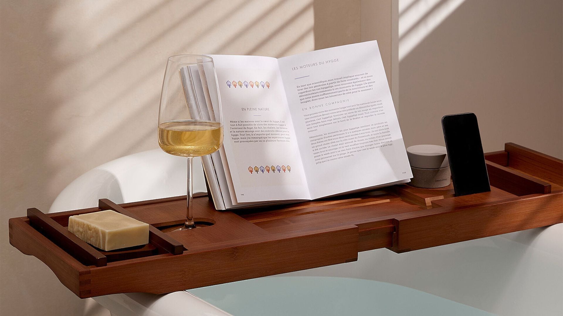 a path tray over a bath carrying a book a bar of soap and a glass of wine